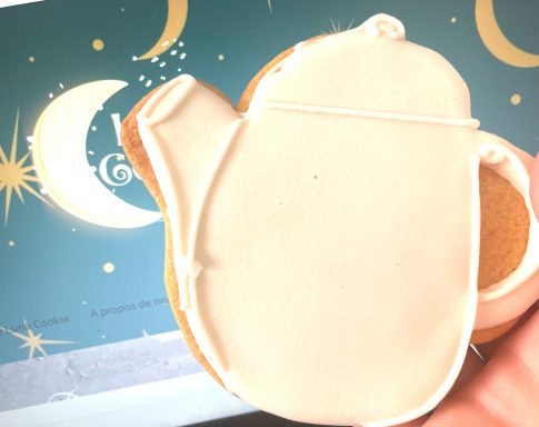 Théière biscuit décoré Gâteau en forme de théière, décoré de glaçage blanc sur fond étoilé.