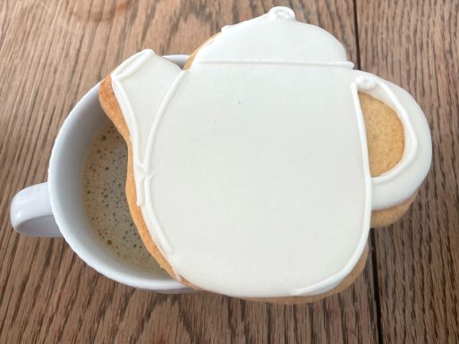 Biscuit décoré théière Un biscuit en forme de théière posé sur une tasse de café.