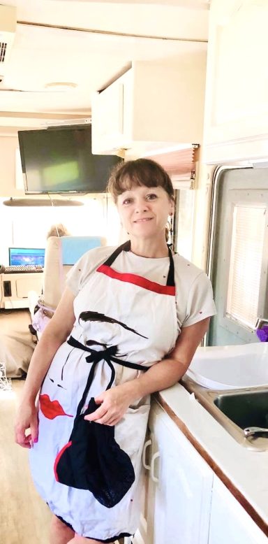 Véronique Femme en tablier dans une cuisine, avec une expression pensive.