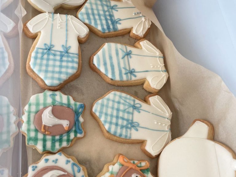biscuits pour mariage Biscuits en forme de vêtements de bébé, décorés de glaçage bleu et de motifs à carreaux.