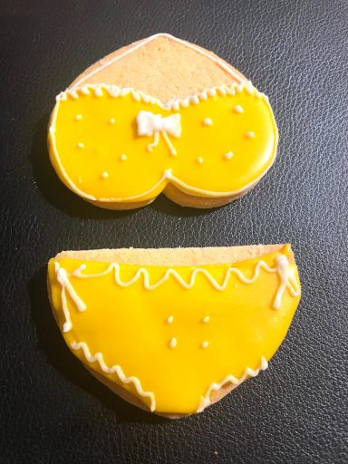 bikini biscuit décoré Biscuits en forme de maillot de bain, colorés en jaune avec des décorations blanches.