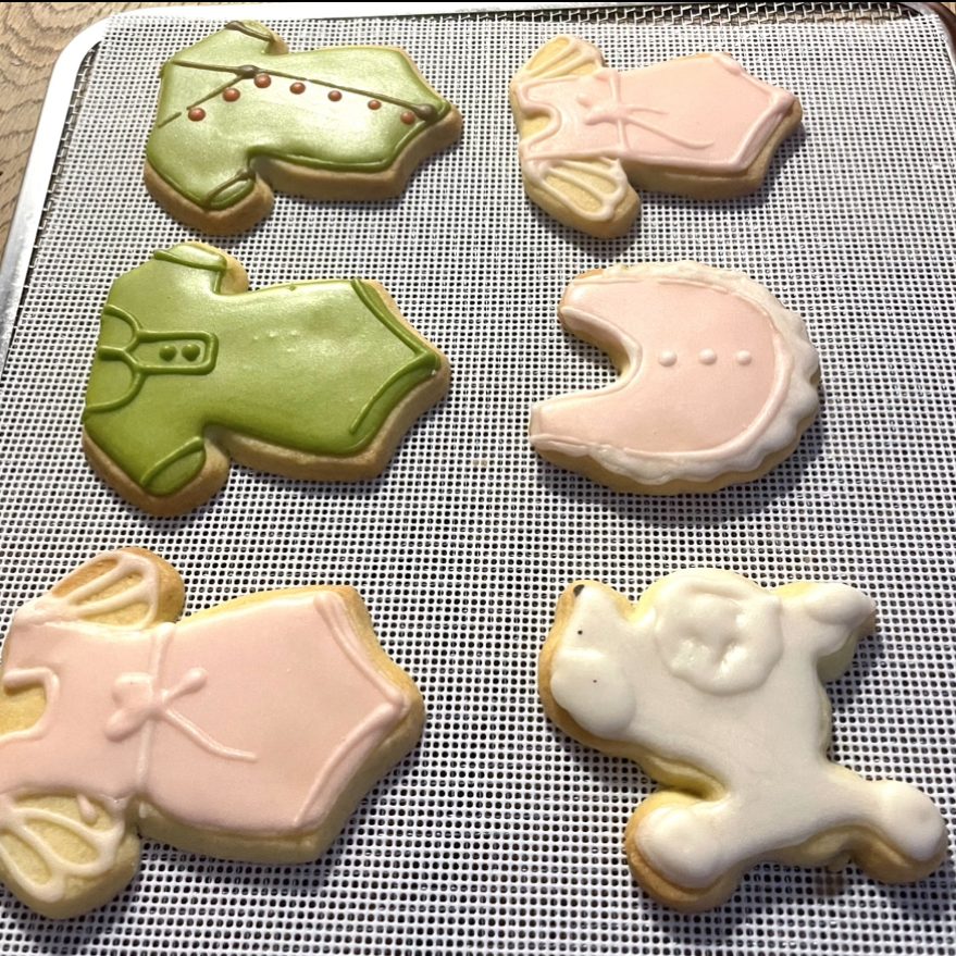 ateliers culinaires et cours d'anglais Biscuits décorés en forme de vêtements et d'animaux, colorés en rose, vert et blanc.